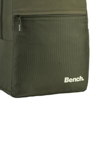 Groene rugzak met een gestructureerd honingraatpatroon aan de voorkant, met een ritszak en een wit "Bench." logo in de rechteronderhoek.