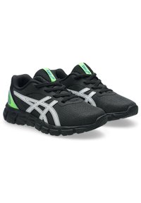 Scarpe sportive nere con tomaia in rete, accenti laterali argento, dettaglio verde sul tallone e suola texture progettata per trazione e supporto.