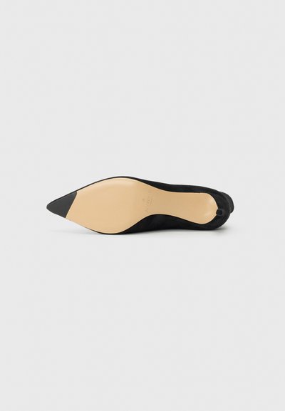 Schwarzes Wildleder-Pumps mit beiger Sohle und schwarzem Absatzende. Das Design zeichnet sich durch eine glatte Textur und eine schlanke Silhouette aus.
