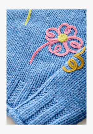 Lyseblå strikket sweater med et tekstureret mønster, med pink og gule broderede blomster- og swirl-designs.