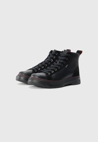 Zapatillas altas negras de materiales de cuero y gamuza, con una suela texturizada negra, cierre de cordones y detalles de costura en rojo.
