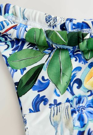 Peldkostīms ar ziedu un lapu rakstu zilā un zaļā krāsā uz balta fona, ar savāktu jostasvietas dizainu komfortam.