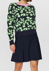 Dzianinowy sweter w kwiatowy wzór w kolorach zielonym i białym na granatowym tle. Posiada różowy ściągacz przy dekolcie i długie rękawy. W zestawie z granatową spódnicą.