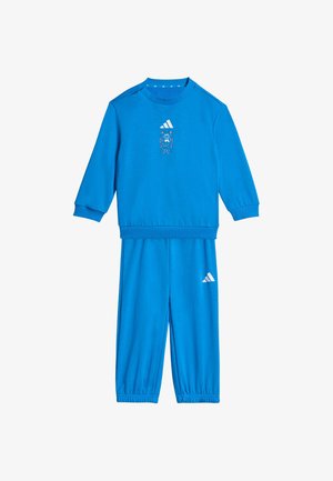 Conjunto azul de sudadera de manga larga y pantalones con puños elásticos, con un pequeño gato de dibujos animados y logo de Adidas en la sudadera y logo en los pantalones.