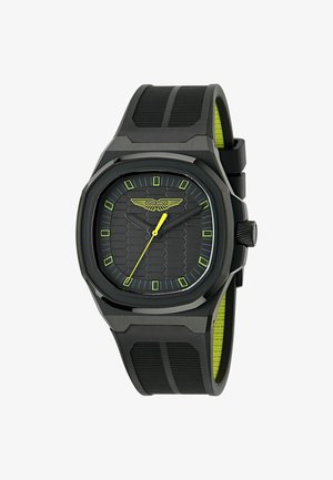 Černé hodinky s hexagonálním texturovaným ciferníkem a žlutými akcenty. Mají silikonový řemínek, osmiúhelníkový pouzdro a luminiscenční hodinové značky.