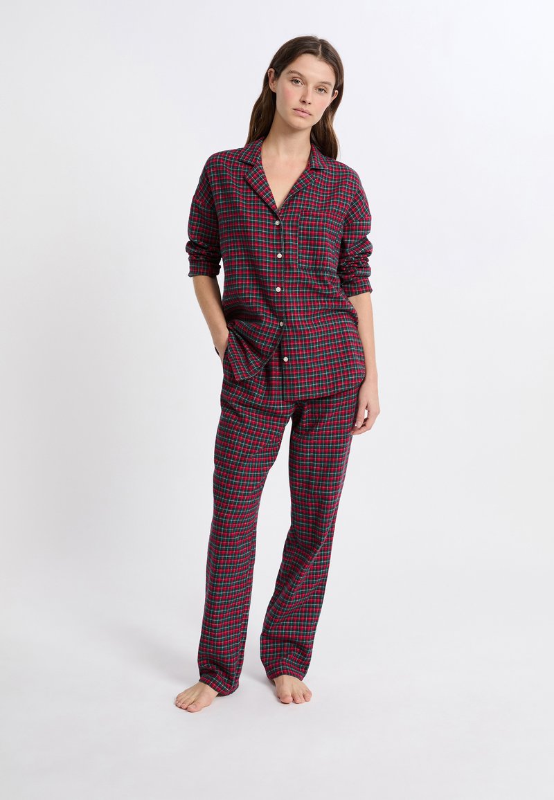 Conjunto de pijama a cuadros rojos y verdes que incluye una camisa de botones de mangas largas y pantalones a juego, fabricado con tela suave.