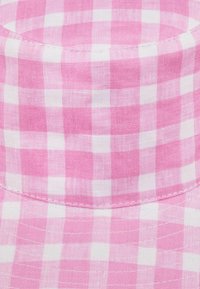 Tissu vichy rose, présentant un motif à carreaux de carrés de rose clair et de rose foncé. Texture lisse avec des coutures visibles le long des bords.