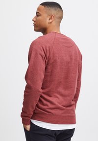 Sweatshirt crewneck bordeaux en tissu doux, doté d'un design à manches raglan et de poignets et d'un ourlet côtelés pour un look ajusté.