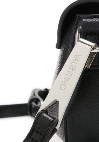Sac en cuir noir avec une surface texturée, doté d'un clip métallique argenté gravé "VALENTINO" et d'une bandoulière détachable.