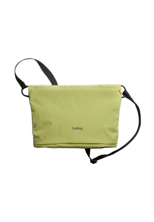 Sac messager en tissu vert avec une finition texturée, bandoulière noire réglable et marquage discret. Il présente une fermeture éclair et un design minimaliste.
