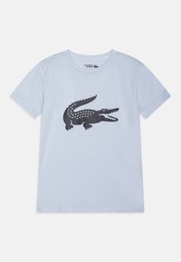 T-shirt en coton bleu clair avec un graphique de crocodile noir au design imprimé. Manches courtes et col rond.