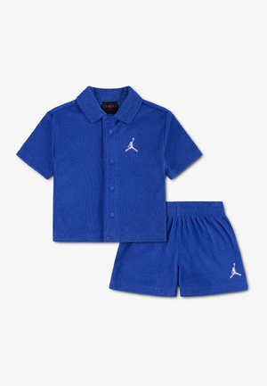 Ensemble chemise à manches courtes boutonnée bleue et short assorti avec logos Jumpman blancs sur la poitrine et la jambe.