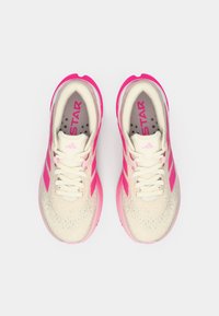 Ελαφριά αθλητικά παπούτσια σε κρεμ απόχρωση με ζωντανές ροζ λεπτομέρειες, που διαθέτουν υφή στο επάνω μέρος, λευκά κορδόνια και τρύπες αερισμού.