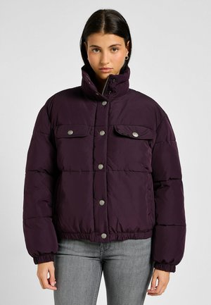 Plumón de color morado oscuro, con un cuello alto, botones a presión y dos bolsillos frontales. El material es suave y acolchado, con puños elásticos.