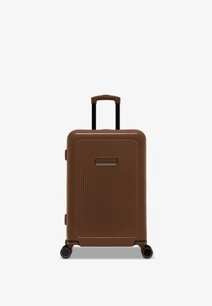 Brown hard-shell suitcase with ridged texture, black telescopic handle, and four wheels for mobility. Logo visible on the front.
