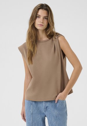 Brun ärmlös topp med rund halsringning, med draperad axeldetalj och mjukt, slätt tyg; matchas med ljusblå texturerade byxor.