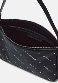 Borsa a spalla nera con pattern testuale bianco "Liebeskind Berlin", con zipper aperto che rivela un interno scuro con tasca interna e etichetta del marchio.