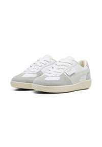 Puma-sneakers med en överdel i vitt läder och ljusgrå mockadetaljer, utrustade med en texturerad gummisula och traditionell snörningsdesign.