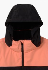 Kapuzenshirt mit schwarzer Kapuze und einem korallenpinken Körper; aus einem glatten, wasserabweisenden Material mit einem zentralen Reißverschluss gefertigt.