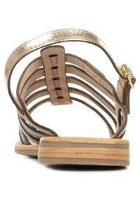 Sandalo metallico d'oro con cinturini, interno in pelle beige e suola in legno. Include una cinghia per la caviglia regolabile con dettagli in metallo dorato.