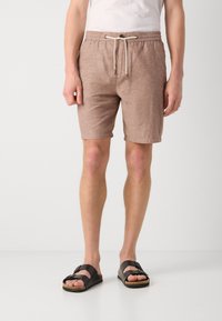 Shorts en lin beige mélangé avec une taille élastique et un cordon de serrage, comprenant deux poches avant et une coupe décontractée, associés à des sandales noires.
