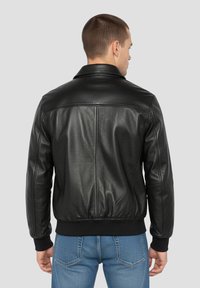 Schwarze Lederjacke mit leicht taillierter Silhouette, gerippten Bündchen und glatter Oberfläche. Verfügt über einen klassischen Kragen und eine hintere Passe als Detail.