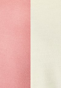 Tissu rose texturé à gauche et tissu ivoire texturé à droite, tous deux présentant un motif fin en relief et une apparence douce.