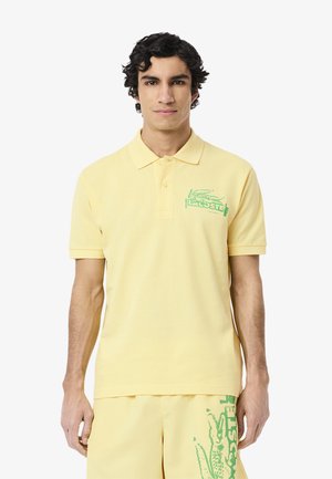 Lichtgele polo shirt van katoen, met een groen Lacoste-logo op de linkerkant van de borst. Korte mouwen en een klassieke kraag.
