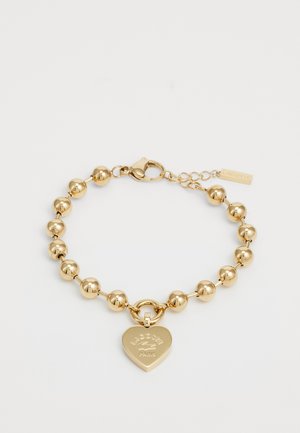 Gold bracelet featuring round beads, a heart-shaped charm with embossed logo, and a secure clasp with a chain extension for adjustability.