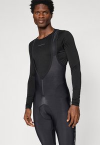 Čierny cyklistický dres s predným zipsom, podloženou sedacou časťou a dlhým čiernym rukávom pod ním; vyrobený z hladkej, elastickej látky.