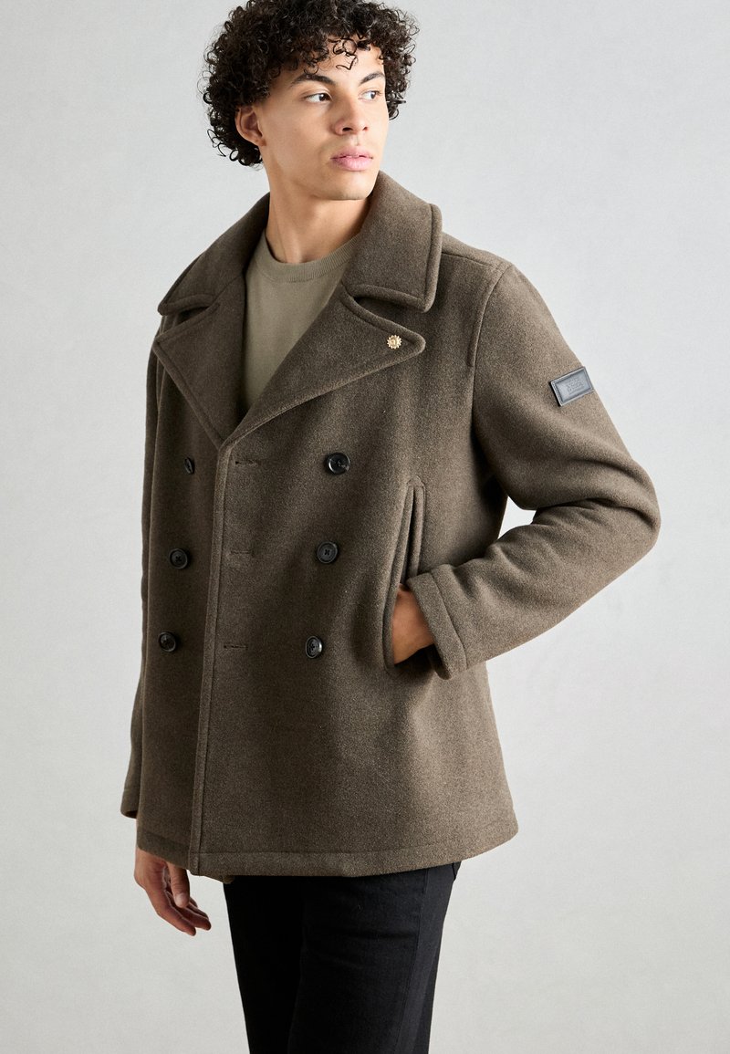 Brun ull peacoat med dobbeltrykt design, sorte knapper, bredt notched krage, sidelommer og et lærpatch på ermet.