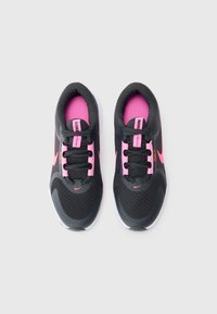 Une paire de chaussures de course Nike noires et roses avec une tige en mesh et des semelles blanches, vue de dessus sur un fond gris clair.