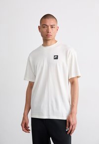 Hvid bomulds T-shirt med korte ærmer og rund halsudskæring. Har et lille sort Nike Air logo på forsiden. Minimalistisk design.
