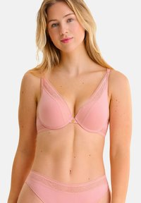 Soutien-gorge rose clair avec une finition lisse, orné de dentelle et d'un motif géométrique sur les bords. Des culottes assorties rose clair sont visibles.
