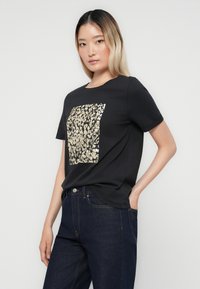 Zwarte t-shirt met korte mouwen, met een gouden en zilveren luipaardpatroon van sequins op de voorkant. Zachte stof, comfortabele pasvorm.