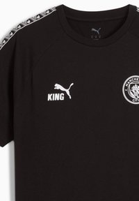 Sort bomulds T-shirt med korte ærmer, hvid "KING" tekst, Puma-logo og Manchester City-emblem på forsiden, med mønstret skulderdetalje.