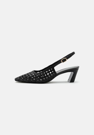 Zapato slingback negro tejido con tacón bajo de bloque y hebilla dorada en la correa lateral, mostrado de perfil sobre un fondo liso.