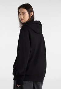 Sweatshirt à capuche noire en tissu doux avec une coupe décontractée. Doté d'une poche kangourou et de poignets côtelés pour plus de confort.