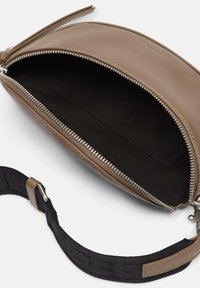 Torebka skórzana w kolorze brązowym z zamkiem błyskawicznym, czarnym wnętrzem i teksturowanym czarnym paskiem z akcentami logo.