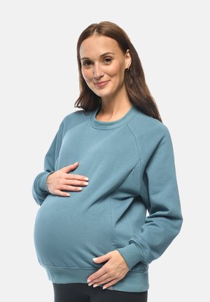 Felpa premaman in morbido tessuto blu. Caratterizzata da un collo rotondo, polsini a coste e una tasca laterale. Vestibilità rilassata per il massimo comfort.