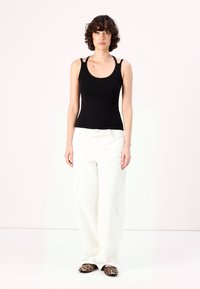 Black tank top with wide straps, paired with high-waisted white wide-leg jeans and leopard print flats. Simple and clean design.