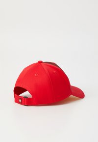 Rote Baseballmütze mit strukturierter Form, ausgestattet mit einem gebogenen Schirm, verstellbarem Riemen hinten und einem kleinen Logo-Tag.