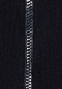 Maglione navy con chiusura centrale a zip e traccia in metallo. Tessuto morbido e lavorato a maglia con una finitura liscia.