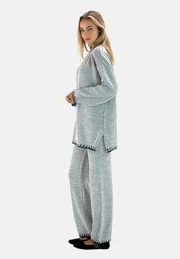 Conjunto de punto gris claro de dos piezas con una parte superior de corte holgado y pantalones a juego, que presentan costuras de acento negras en los dobladillos y puños.