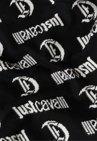 Sort stof med hvidt gentaget "Just Cavalli" tekst og stiliserede "J" logoer i et vævet mønster.