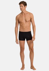 Black boxer briefs made of smooth fabric, featuring a fitted design, short legs, and a soft waistband. No visible patterns or accents.