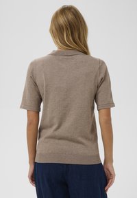 Polo shirt maro cu mânecă scurtă, cu guler, margine ribbed și textură netedă. Material ușor, cu variații subtile de culoare.
