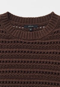 Nahaufnahme eines braunen, gestrickten Pulloverkragens mit geripptem Halsausschnitt und schwarzem Etikett, auf dem der Markenname "OPUS" und die Größe 36 zu sehen sind.