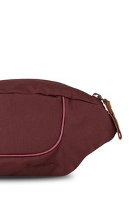 Bordeauxfarbene Stofftasche mit abgerundeter Form, rosa Paspel und Lederreisverschluss. Logo auf der Seite eingeprägt. Glatte Textur.