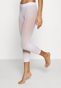 Weiße, durchsichtige Capri-Leggings mit tailliertem Design, elastischem Taillenbund und geschwungener Saumgestaltung am Knöchel. Glatte Textur überall.